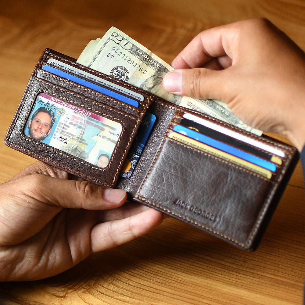 Brown leather wallet with money and cards held by a hand on a wooden surface