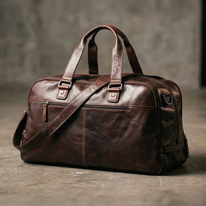 Brown leather duffel bag on a textured surface with a neutral background