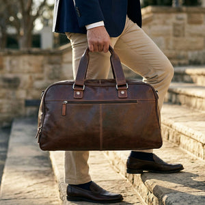 Person holding a brown leather bag outdoors on stone steps