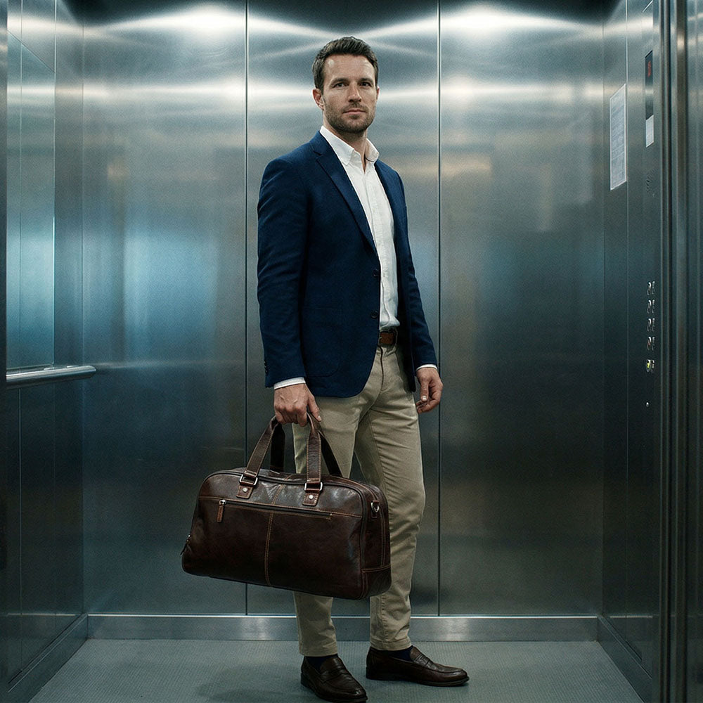 Man in a suit holding a leather bag inside an elevator