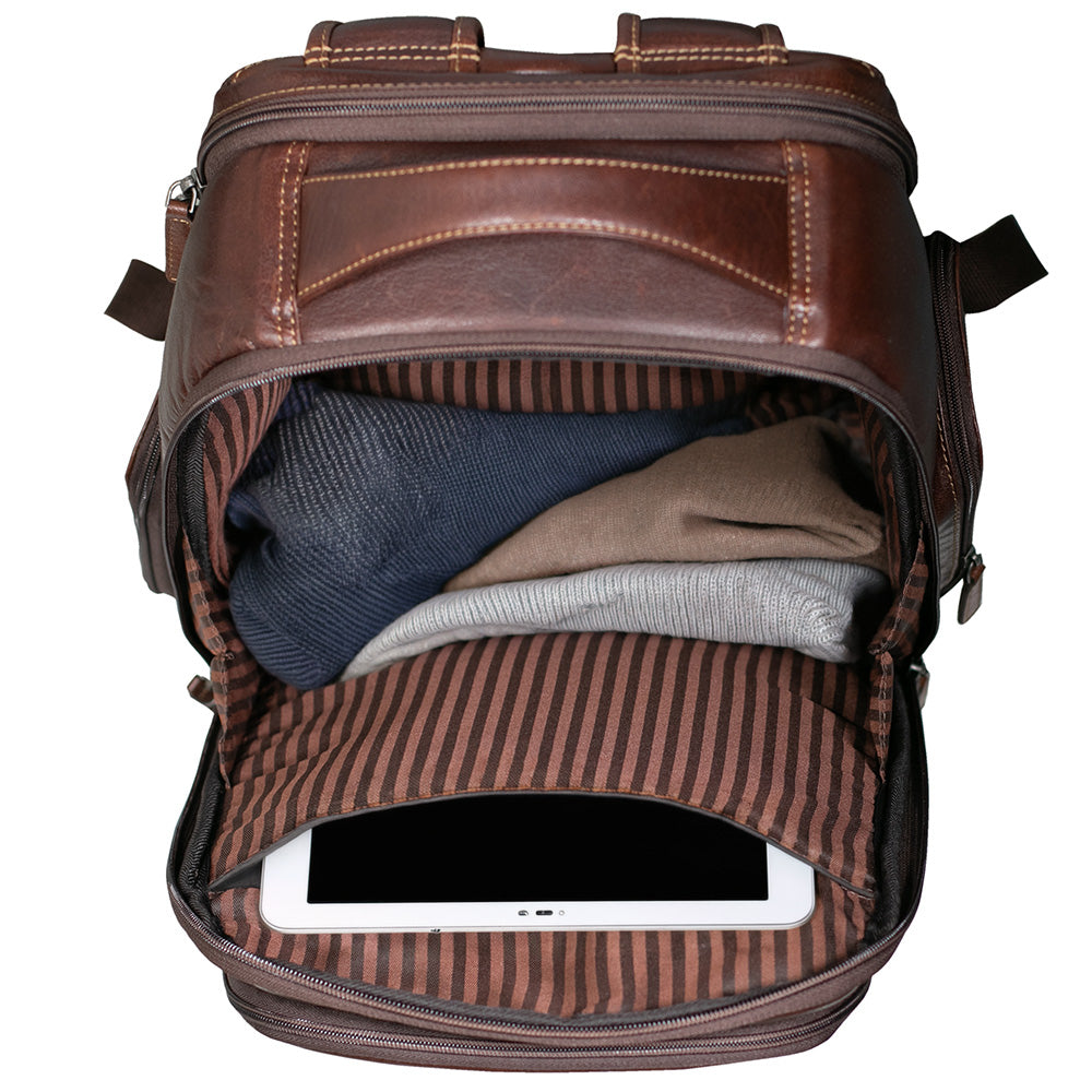 A brown leather backpack shown open from a top-down view, revealing a striped interior lining and folded clothing inside, with a tablet partially visible in the lower compartment.