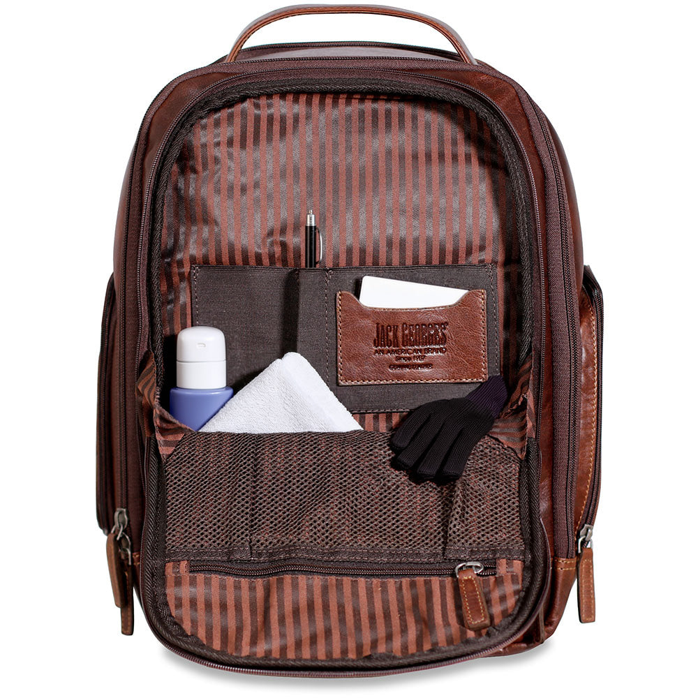 A brown leather and striped nylon backpack shown open, displaying its interior organization with multiple pockets holding a pen, card, bottle, tissue, gloves, and other small accessories. The brand name 'JACK BARRIS' is embossed on a brown leather patch on the front pocket.