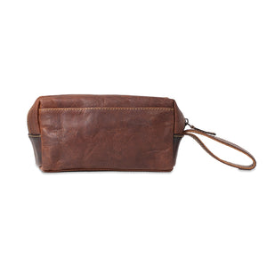 Brown leather clutch bag with wrist strap on a white background